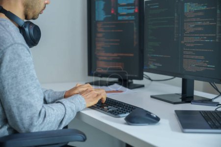 Téléchargez les photos : Asiatique homme invite ingénieur développer application de codage avec des données logicielles assis devant moniteur d'ordinateur au bureau - en image libre de droit