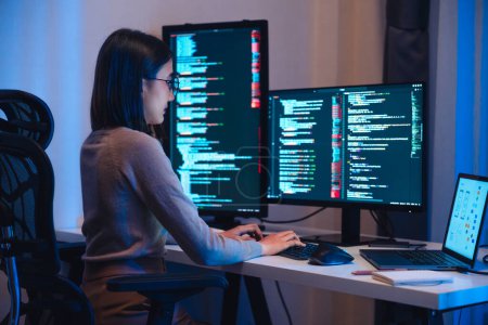 Téléchargez les photos : Asiatique femme développement de logiciels de travail sur le codage écran d'ordinateur et organigramme la nuit dans le bureau moderne - en image libre de droit