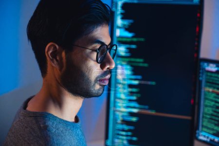 Indische Softwareentwicklung arbeitet an der Programmierung von Computerbildschirm und Flussdiagramm in der Nacht im modernen Büro