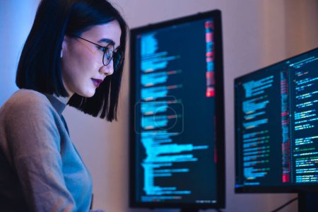Téléchargez les photos : Asiatique femme développement de logiciels de travail sur le codage écran d'ordinateur et organigramme la nuit dans le bureau moderne - en image libre de droit