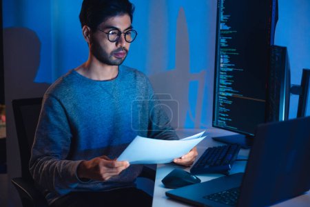 Téléchargez les photos : Développement de logiciels indiens travaillant sur le codage d'écran d'ordinateur et d'organigramme la nuit dans le bureau moderne - en image libre de droit