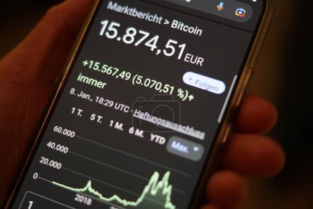Téléchargez les photos : The hand of a man holding a mobile phone and checking the Bitcoin course - rising courses - Google Chrome search, Radolfzell am Bodensee, January 9th, 2023 - en image libre de droit