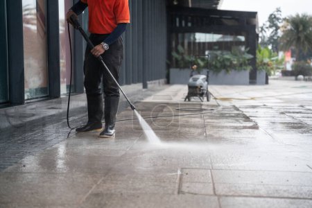 Téléchargez les photos : Cleaning staff hoses a portable car for washing the concrete floor with high-pressure water jets. - en image libre de droit