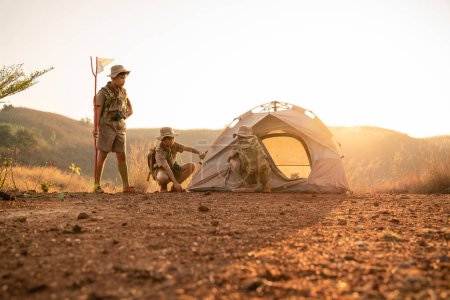 Foto de Teamwork of Three Boy Scouts attending Scout camp pitching their tents in a Boy Scout camp on a mountain near sunset. - Imagen libre de derechos