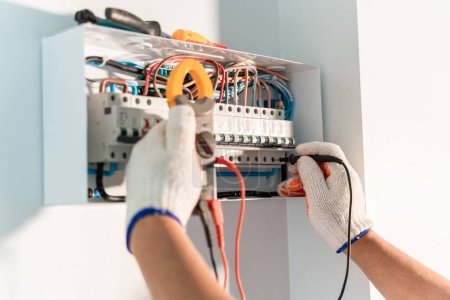 Photo for Hand of Electrician engineer work tester measuring voltage and current of power electric line in electrical cabinet control. Medium voltage switchgear - Royalty Free Image