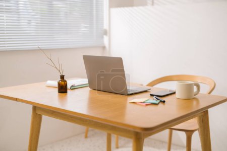 Téléchargez les photos : Ordinateur portable et documents sur bureau en bois à la maison, espace de travail confortable, lieu de travail avec ordinateur dans l'appartement. concept de travail à domicile - en image libre de droit