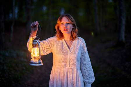Téléchargez les photos : Rousse fille en robe blanche dans la forêt sombre - en image libre de droit