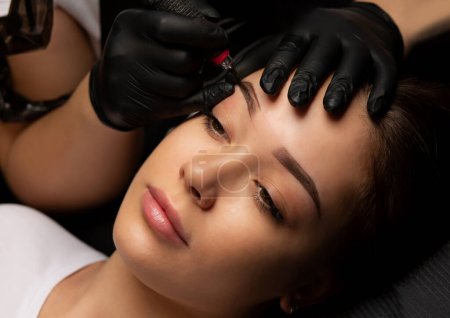Photo for Process of creating permanent brow tattoo with a machine at beauty salon - Royalty Free Image