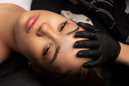 Photo for Process of creating permanent brow makeup with a machine at beauty salon. Closeup shot - Royalty Free Image