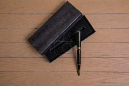 elegant metal fountain pen in black color with gold details with black velvet case on wooden background