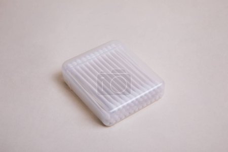 Paket Wattestäbchen mit Plastikstift in transparentem Kunststoffetui auf beigem Hintergrund 3 / 4 Tauchgang Ansicht