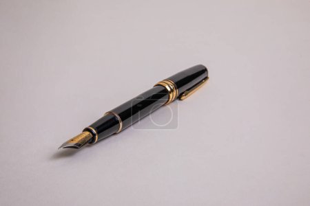 elegant black metal fountain pen with gold details low angle view on beige background