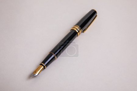 elegant black metal fountain pen with gold details overhead view on beige background