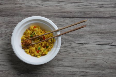 Photo for Food take out - concept - curry rice with meat on a chinet disposable paper bowl and wooden disposable chopsticks on wooden table, space for text, eco friendly - Royalty Free Image