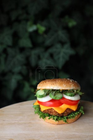 Photo for Homemade hamburger with cheese, vegetables on a brown table with a dark background and place for text. Takeaway concept. Rustic style - Royalty Free Image