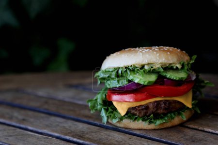 Téléchargez les photos : Hamburger au fromage, légumes sur une table brune avec un fond sombre et un endroit pour le texte. Concept des plats à emporter. - en image libre de droit