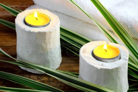 Téléchargez les photos : Bougeoirs en bois blanc avec feuilles de bambou et serviettes sur fond bois foncé - spa et détente - en image libre de droit