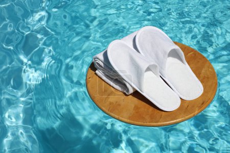 Téléchargez les photos : Vue rapprochée des pantoufles et serviettes blanches sur cercle en bois dans la piscine. Balnéo, spa, hôtel, concept maison - en image libre de droit