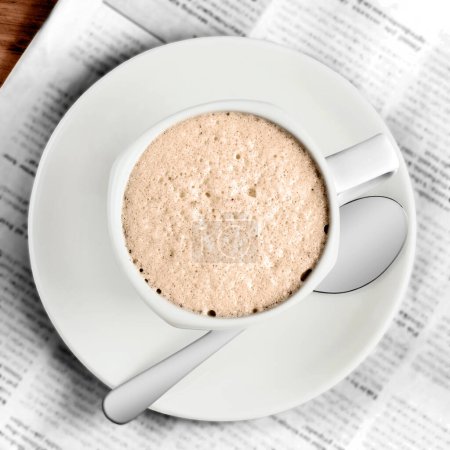 Téléchargez les photos : Une tasse de café avec une cuillère sur fond de journal - en image libre de droit