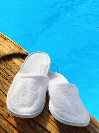 Photo for Spa, hotel, home, wellness slippers with rolled towels on pier with water background, summer time, space for text - Royalty Free Image