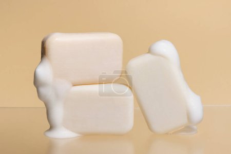 Foto de Piezas de jabón ligero con espuma sobre un fondo beige aislado. Cosmética natural para el cuidado de la piel. - Imagen libre de derechos