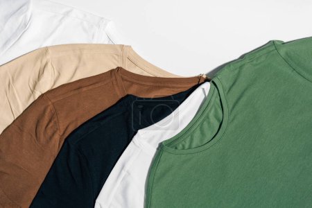 T-shirts blancs, beiges et verts disposés sur un fond blanc isolé. Le concept de choisir des vêtements et de remplacer la garde-robe