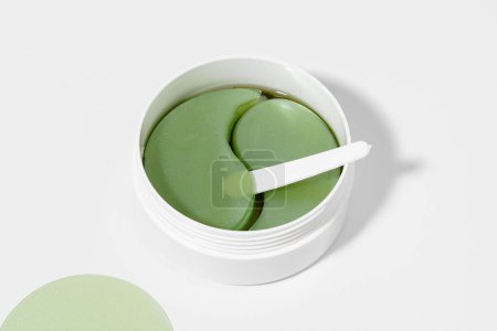 Téléchargez les photos : Gros plan d'un pot de taches d'hydrogel vert avec extrait d'algue et thé. Concept de produits pour soins de la peau sous les yeux, hydratants et anti-cernes - en image libre de droit
