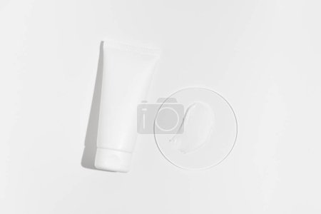 Weiße Cremetuben-Attrappe und Schmierprobe auf Glas auf weißem, isoliertem Hintergrund. Das Konzept der Ästhetik, Schönheit, Hautpflege. Image für Ihr Design.