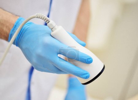 Photo for The cosmetologist holds an ultrasound cavitation device in his hands - a procedure for removing fat. Hardware cosmetology - Royalty Free Image