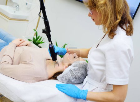 A cosmetologist uses a CO2 fractional ablative laser to rejuvenate the skin and remove scars in a modern cosmetic beauty clinic.