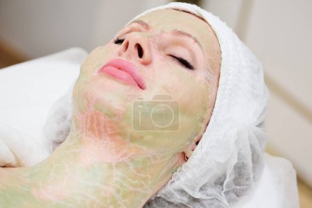 Foto de Un cosmetólogo realiza un procedimiento de terapia enzimática para una paciente femenina. El médico dermatólogo usa una máscara enzimática - Imagen libre de derechos