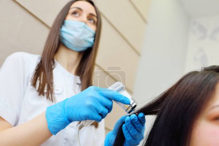 Photo for Doctor cosmetologist dermatologist diagnoses the condition of the patients hair using a trichoscope. Trichoscopy - computer examination of the scalp and hair - Royalty Free Image