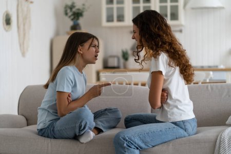 Photo for Angry emotional teen girl adolescent daughter fighting with mother parent at home while sitting in front of each other on sofa, selective focus. Problems between teenagers and parents - Royalty Free Image