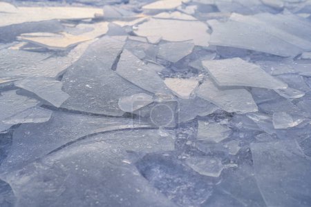 Téléchargez les photos : Gros plan des fissures de glace sur le lac gelé en hiver. Couche d'eau glacée au sommet de la rivière. Étang couvert de glace - en image libre de droit