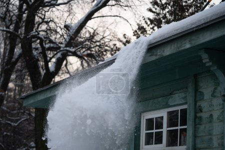 Dach mit Schaufel vom Schnee befreien. Verletzungsgefahr durch Schnee oder herabfallende Eiszapfen. Arbeiter räumen Schnee von alten Holzgebäuden. Winterdienst- und Aktivitätskonzept