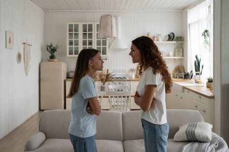 Téléchargez les photos : Emotional stepmom and teen stepdaughter. Naughty adolescent girl arguing with mother at home, being rude with parent. Troubled teen child daughter and her mom quarreling, yelling at each other - en image libre de droit