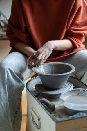 Photo for Ceramic master creating handmade stoneware on wheel in studio, making wheel-thrown ceramics, forming clay into shape. Mindful craft of pottery and art therapy concept - Royalty Free Image
