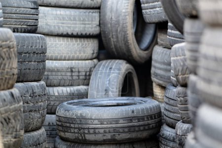 Photo for Old used rubber tires stacked with high piles. Tyre dump. Hazardous waste requiring recycling and disposal. - Royalty Free Image