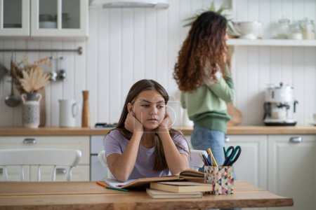 Photo for Sad frustrated schoolgirl sitting at kitchen table with textbooks, needs help with homework. Kid child having difficulties with learning. Parents participation in child educational success - Royalty Free Image