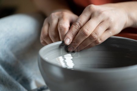 Foto de Close up of female hands molding wet clay on wheel, shaping final pottery product, potter making unique handmade stoneware, selective focus. Stress-relieving hobbies, ceramics and mental heath - Imagen libre de derechos