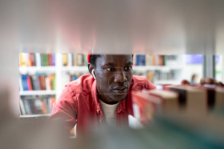 Photo for African American student man choosing book in college library. Black guy learning in university. Male preparing for literature test or exam. Ethnic teenager study in high school. Education concept - Royalty Free Image