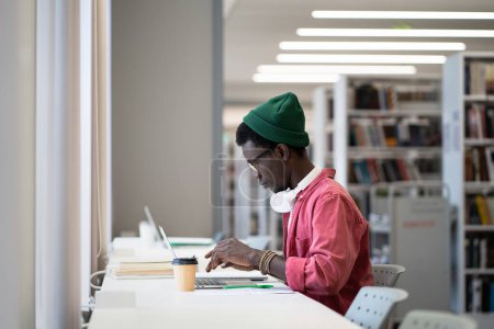 Photo for Focused student black man prepare for exam online on laptop using wireless computer for remote education. African guy sit at university library or campus studying. Freelancer male writer at work - Royalty Free Image