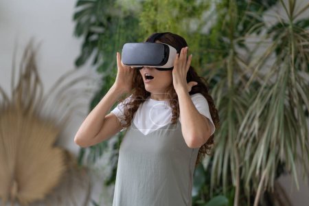 Photo for Woman in vr goggles happy smiling interacting with virtual reality technology after work to relax in home garden. Young female spend weekend testing new gaming equipment for video games simulation - Royalty Free Image
