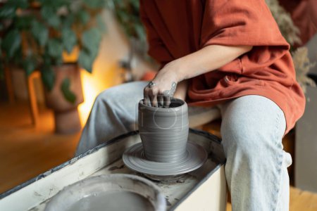 Photo for Close up of female shaping walls of vase on rotating pottery wheel while working in studio, selective focus. Woman forming clay into shape, visiting ceramics masterclass to relieve stress, cropped - Royalty Free Image