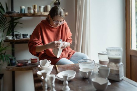 Photo for From passion to owner of exclusive interior ceramics store. Interesting process of making pottery with your own hands working with raw clay preparation for glazing and firing. Modern ceramic workshop. - Royalty Free Image