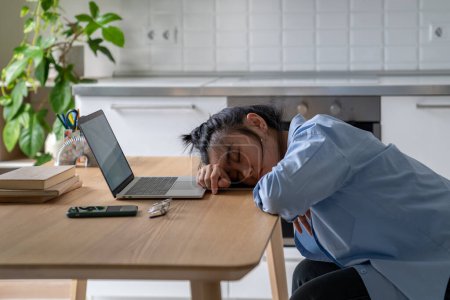 Photo for Exhausted Asian woman sits overworked needs rest fatigue taking nap near laptop. Tired Chinese girl student or freelancer fell asleep on table while long time works remotely or online studying at home - Royalty Free Image