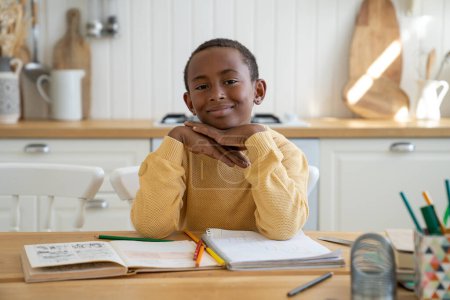 Photo for Happy pleased small boy folding palms together touch chin sit at table with colourful pencils after drawing think about new day wish. Smiling hopeful kid schoolboy satisfied looking at camera daydream - Royalty Free Image