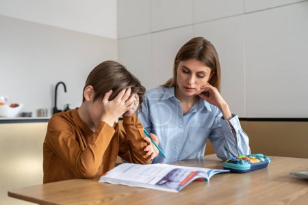 Photo for Upset stressed child boy feeling frustrated while doing homework with mom at home. Kid sitting at kitchen table with teacher tutor having difficulties in learning. Problems with homeschooling - Royalty Free Image