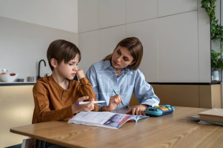 Photo for Upset stressed child boy feeling frustrated while doing homework with mom at home. Kid sitting at kitchen table with teacher tutor having difficulties in learning. Problems with homeschooling - Royalty Free Image