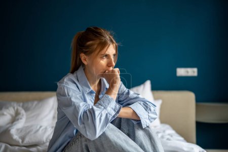Photo for Exhausted worried middle age woman bit fingers nervously sit on bed alone at home. Depressed tired female suffering hopeless, thinking about problems, divorce, break up, lost in bad thoughts troubles - Royalty Free Image
